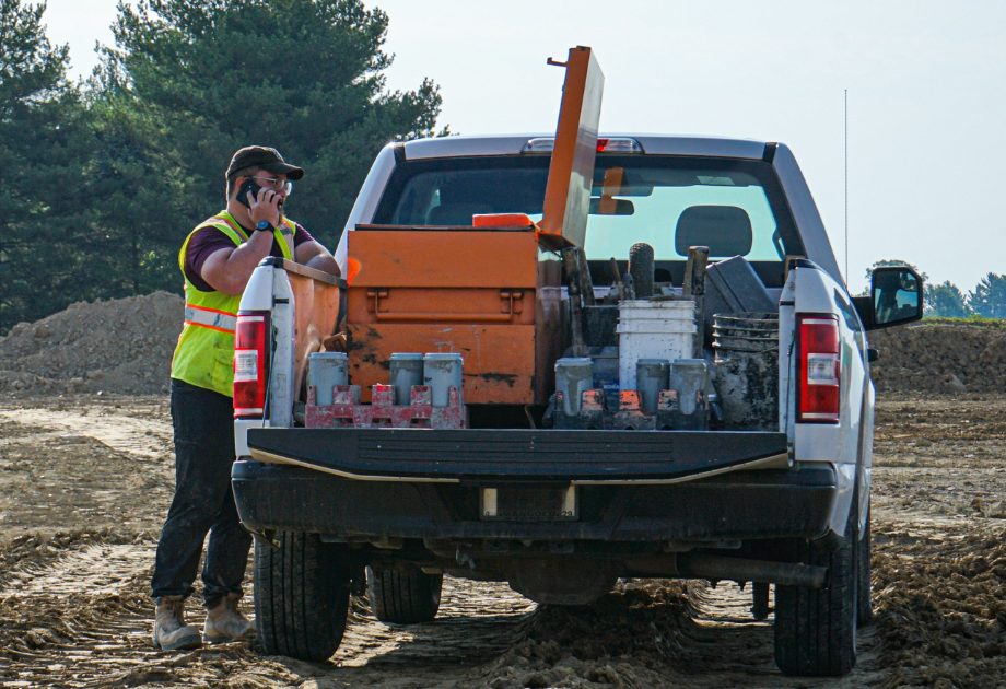 man leaning on his work truck, talking on the phone